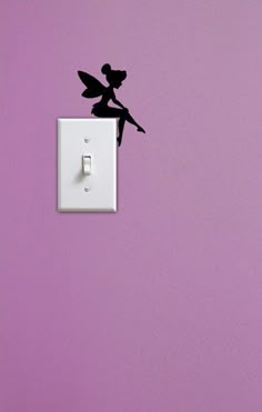 a fairy tinker sitting on top of a light switch cover with the silhouette of a fairy