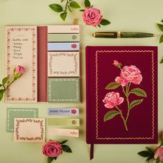 a notebook with pink flowers on it next to some cards