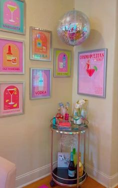 a bar cart in the corner of a room with posters on the wall and a disco ball hanging above it