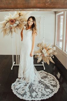 a woman in a white dress standing next to a flower arrangement on a black and white rug