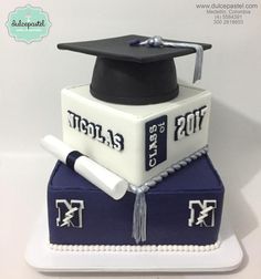 a graduation cake with a mortar and diploma cap on top, sitting on a white plate