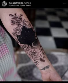 a woman's arm with flowers and stars on it, while she is holding her hand in the air