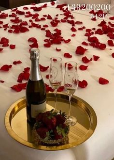 two glasses of wine on a tray with rose petals