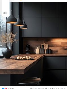 an image of a kitchen setting with black cabinets and wood counter tops, along with lights above the island