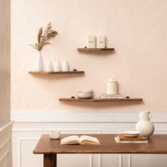 a wooden table topped with two shelves filled with books and vases next to each other