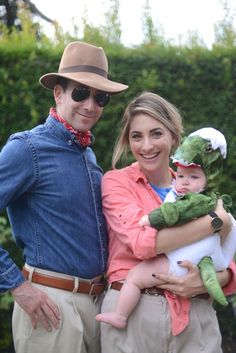 a man and woman holding a baby in their arms while standing next to each other