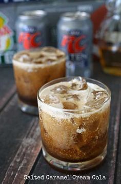 two glasses filled with ice cream sitting on top of a table next to cans of soda