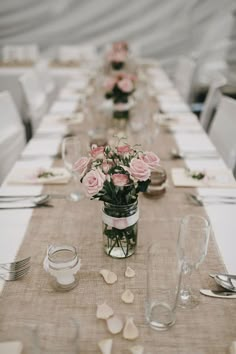 the table is set with pink roses in mason jars and place settings for guests to sit at