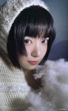 a woman with black hair wearing a white knitted hood