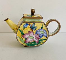 a ceramic teapot with flowers painted on it