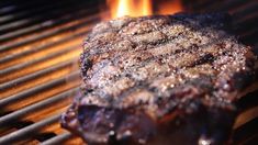 a steak is cooking on the grill with flames