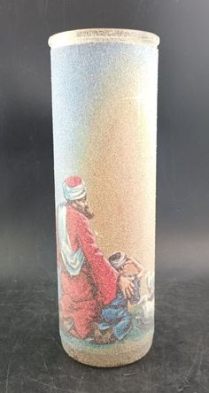 a glass with a painting on it sitting on a table next to a black background