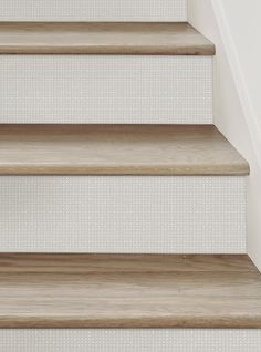 a close up view of some stairs with white wall and wood flooring in the background