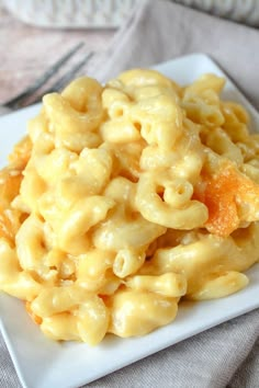 a white plate topped with macaroni and cheese on top of a gray cloth