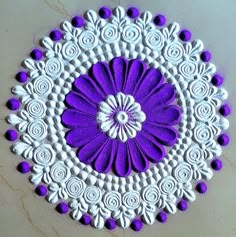 a purple and white doily on a table with some flowers in the center,