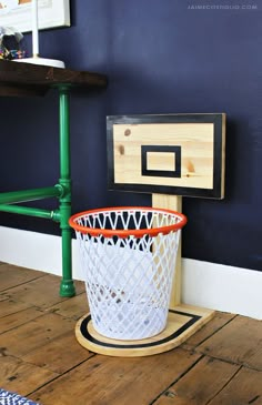 a basketball hoop in the corner of a room next to a white basket on a wooden stand