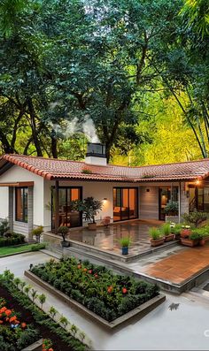 a house in the middle of some trees and plants with lights on it's roof