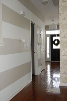 an empty hallway with wood floors and striped wallpaper