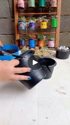 a person's hand is holding a plastic container with plants in it on a table