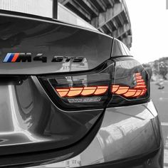 the rear end of a bmw car parked in front of a tall building with an american flag on it