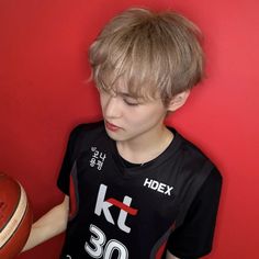 a young boy holding a basketball in front of a red wall