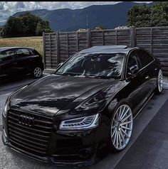 two cars parked next to each other in front of a fence