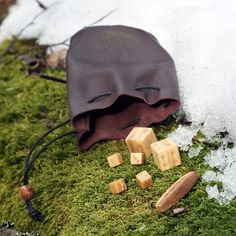 a brown bag sitting on top of a green moss covered ground next to small pieces of wood