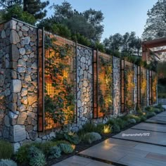 a stone wall with plants growing on it and some lights in the corner next to it