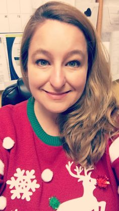 a woman in a red christmas sweater smiling at the camera