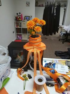 an arrangement of orange flowers in a vase on a table with ribbons and other items