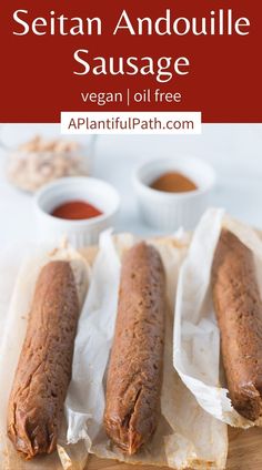 three hot dogs sitting on top of parchment paper next to dipping sauce in small bowls