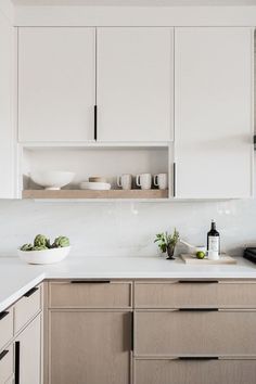 a kitchen with white cupboards and wooden cabinets in the center, along with bowls on the countertop