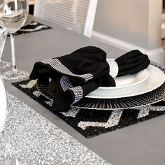 the table is set with black and white plates, silver napkins, and wine glasses