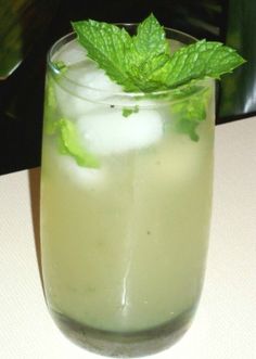 a glass filled with ice and mint on top of a table