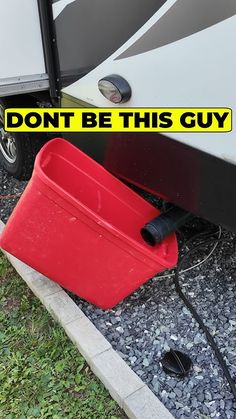 a red bucket sitting on the ground next to a white and black motor home with text that reads, don't be this guy