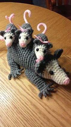 three small crocheted animals sitting on top of a wooden table