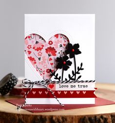 a card with two hearts and flowers on top of a wooden table next to a brush