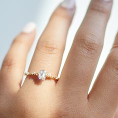 a woman's hand with a diamond ring on top of her left hand,