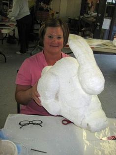 a woman sitting at a table with a large stuffed animal on it's back