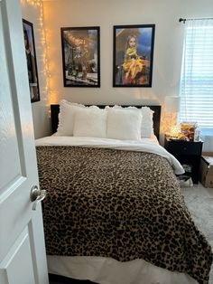 a bedroom with two pictures on the wall and a leopard print bed spread in front of it