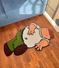 a rug with a cartoon character laying on the floor in front of a blue couch