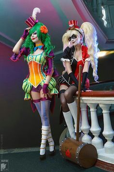 two women dressed up as clowns sitting next to each other on top of a table