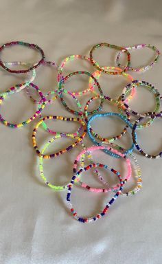 a bunch of bracelets sitting on top of a white sheet covered in lots of beads