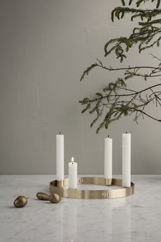 four white candles sitting on top of a marble table next to a potted plant