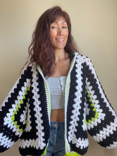 a woman wearing a black and white crochet jacket with green trim smiling at the camera