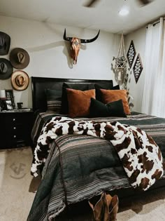 a bedroom with a cow print comforter and pillows on the bed, along with cowboy decor