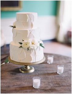 a white wedding cake sitting on top of a wooden table