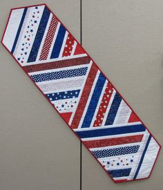 a red, white and blue tie sitting on top of a wall next to a clock