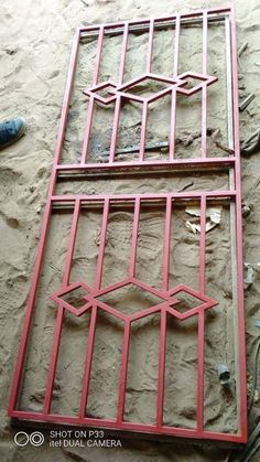 a red metal window frame sitting on top of a wall next to a pair of shoes