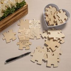 a heart shaped box filled with wooden puzzles next to a pen and flower arrangement